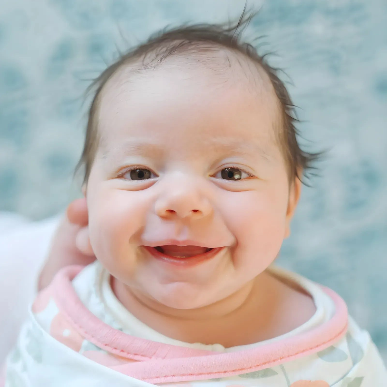 A newborn in a soft pastel nursery palette